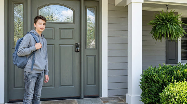Teen with backpack arriving home beside a Wi-Fi smart lock on a grey-green wood front door — keyless entry under $200