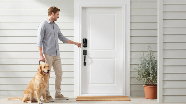 Man with dog using fingerprint smart lock at white front door — keypad, fingerprint and smart lock comparison guide